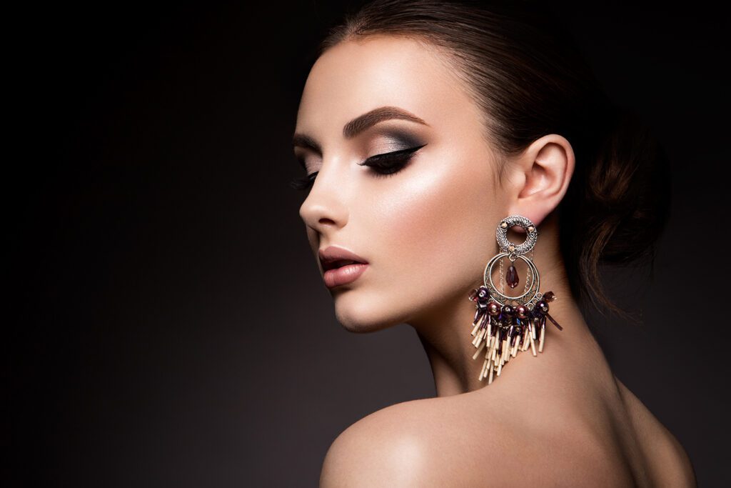 A woman with long earrings and dark eye shadow.
