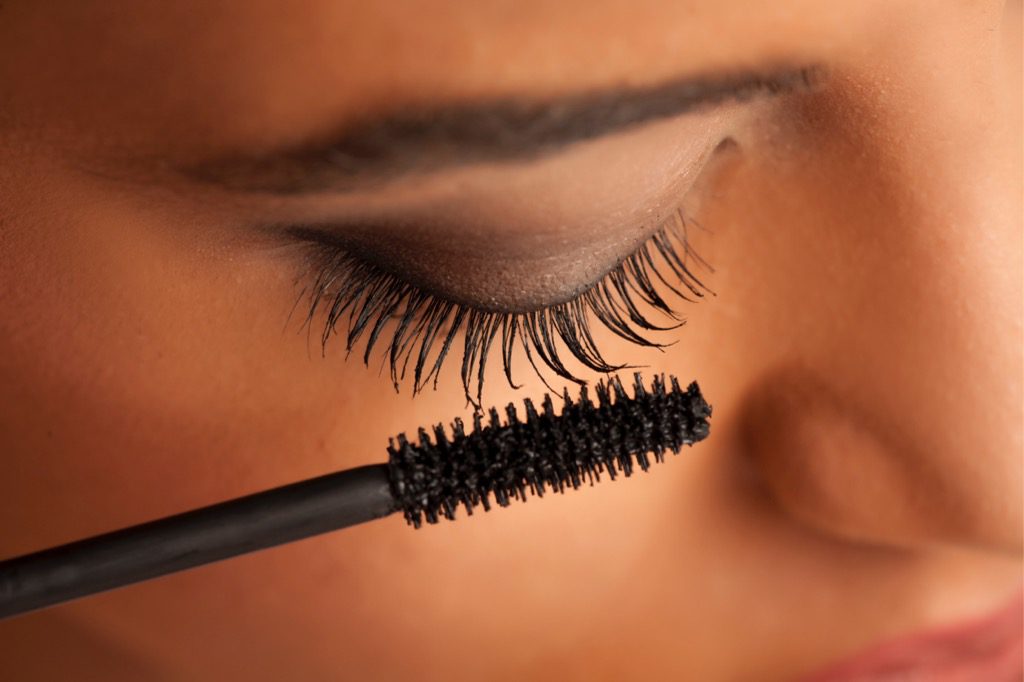 A close up of a person putting mascara on their lashes