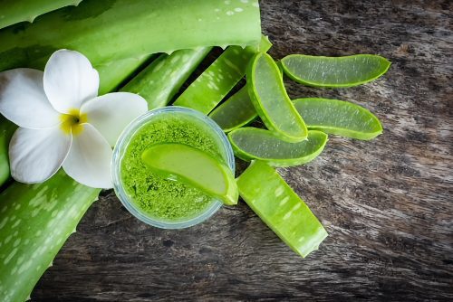 A wooden table topped with green vegetables and a flower.