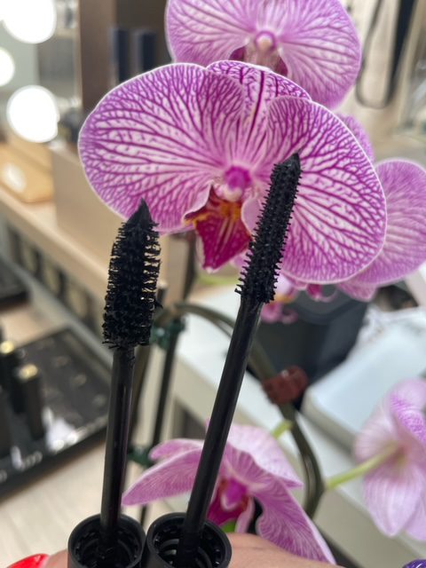 A close up of two purple flowers with black mascara