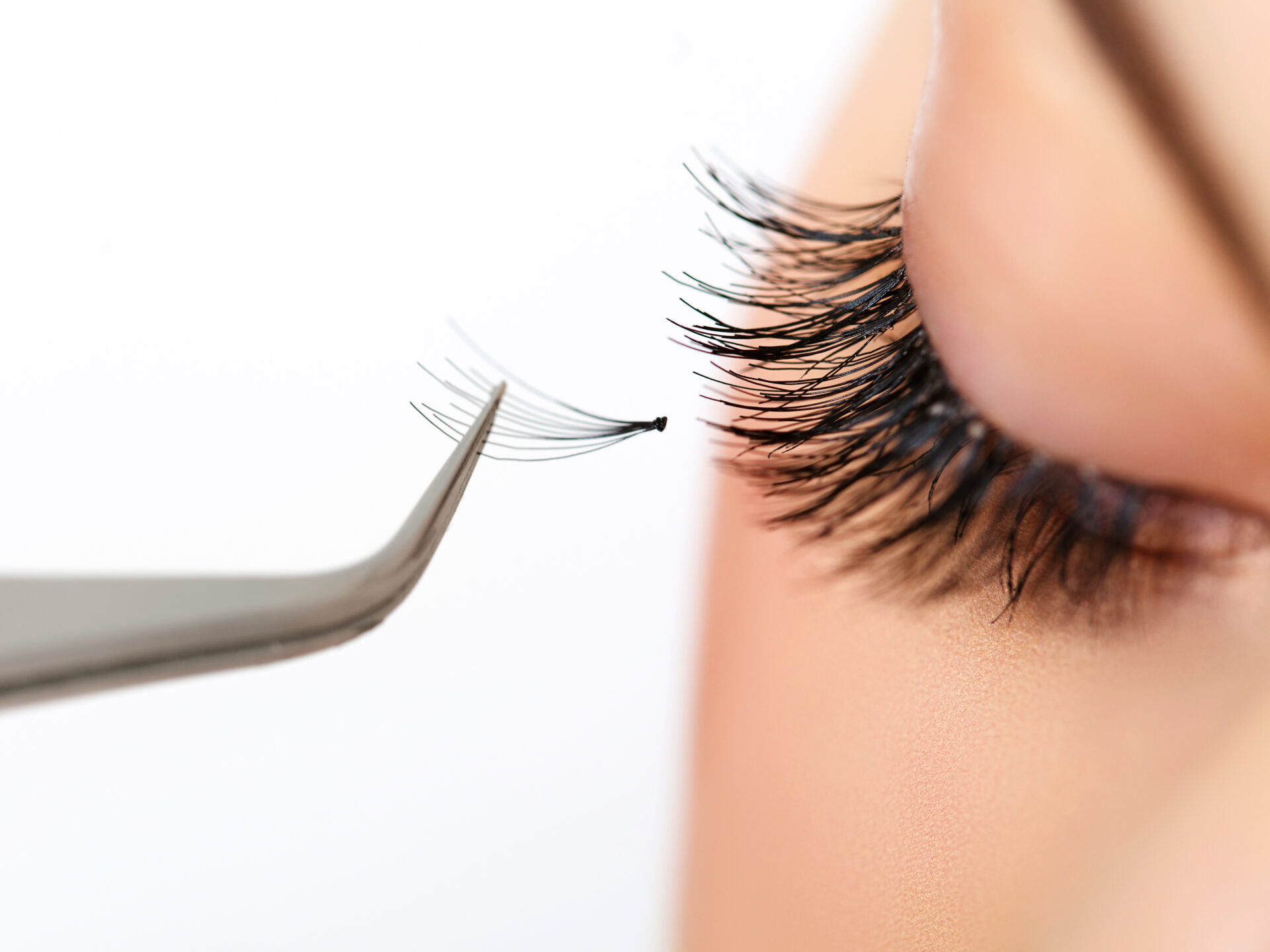 A woman is getting her eyelashes cut off.